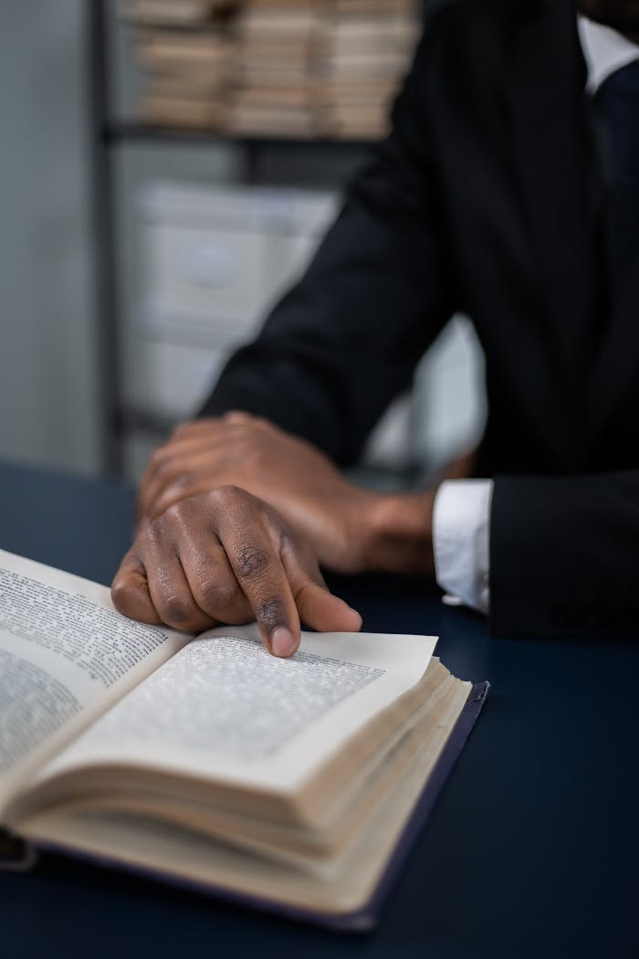 A close-up view of a person's hand navigating text in an open book, ideal for education or learning concepts.